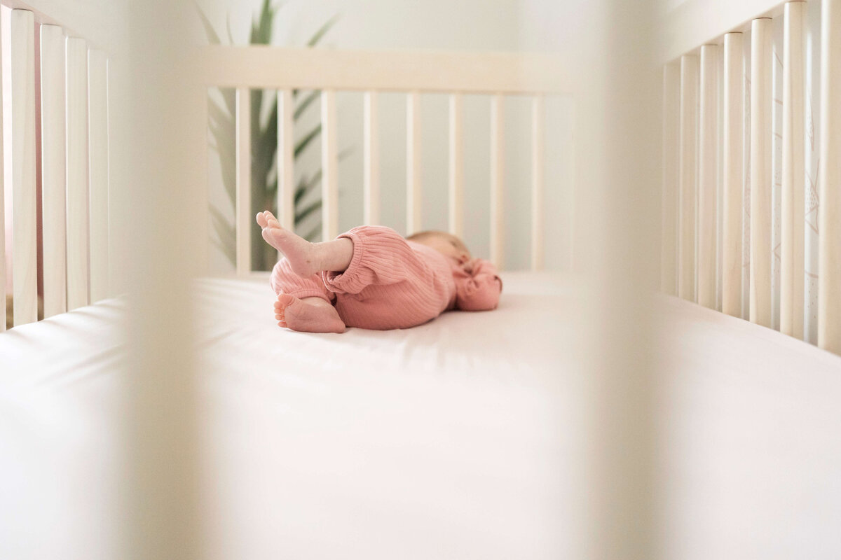 Newborn girl in crib with focus on her feet
