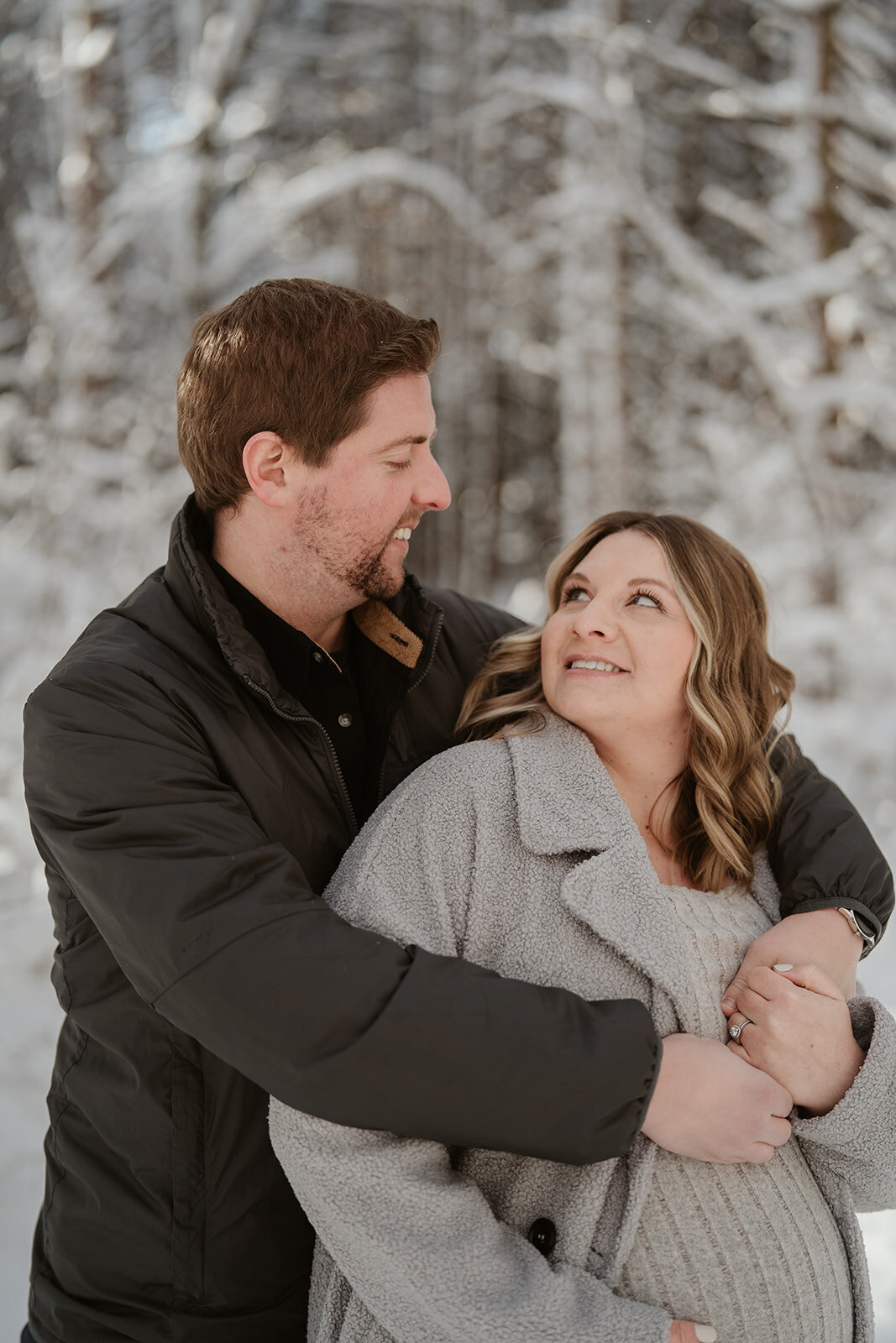 Couple smiling together in snowy pines during maternity session at Al Sabo Land Preserve 