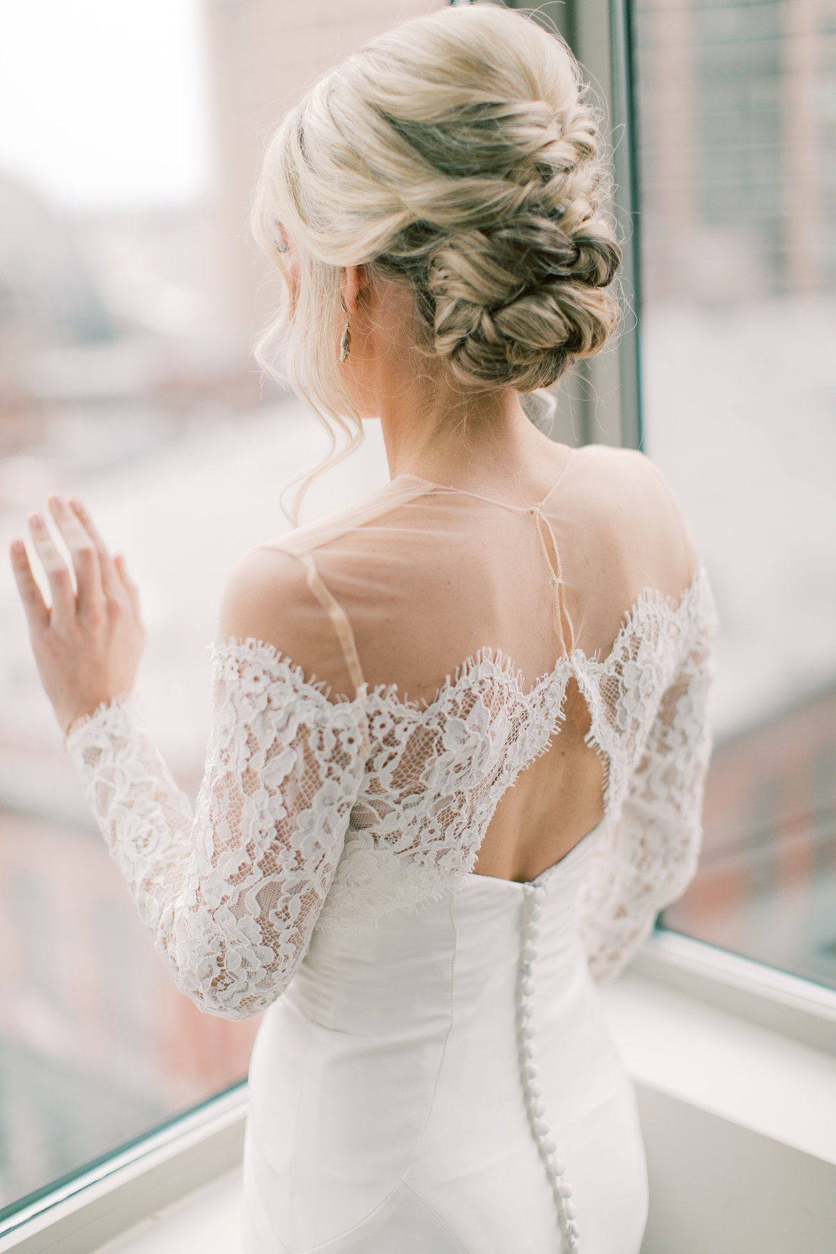 bride looking out window in lace wedding gown