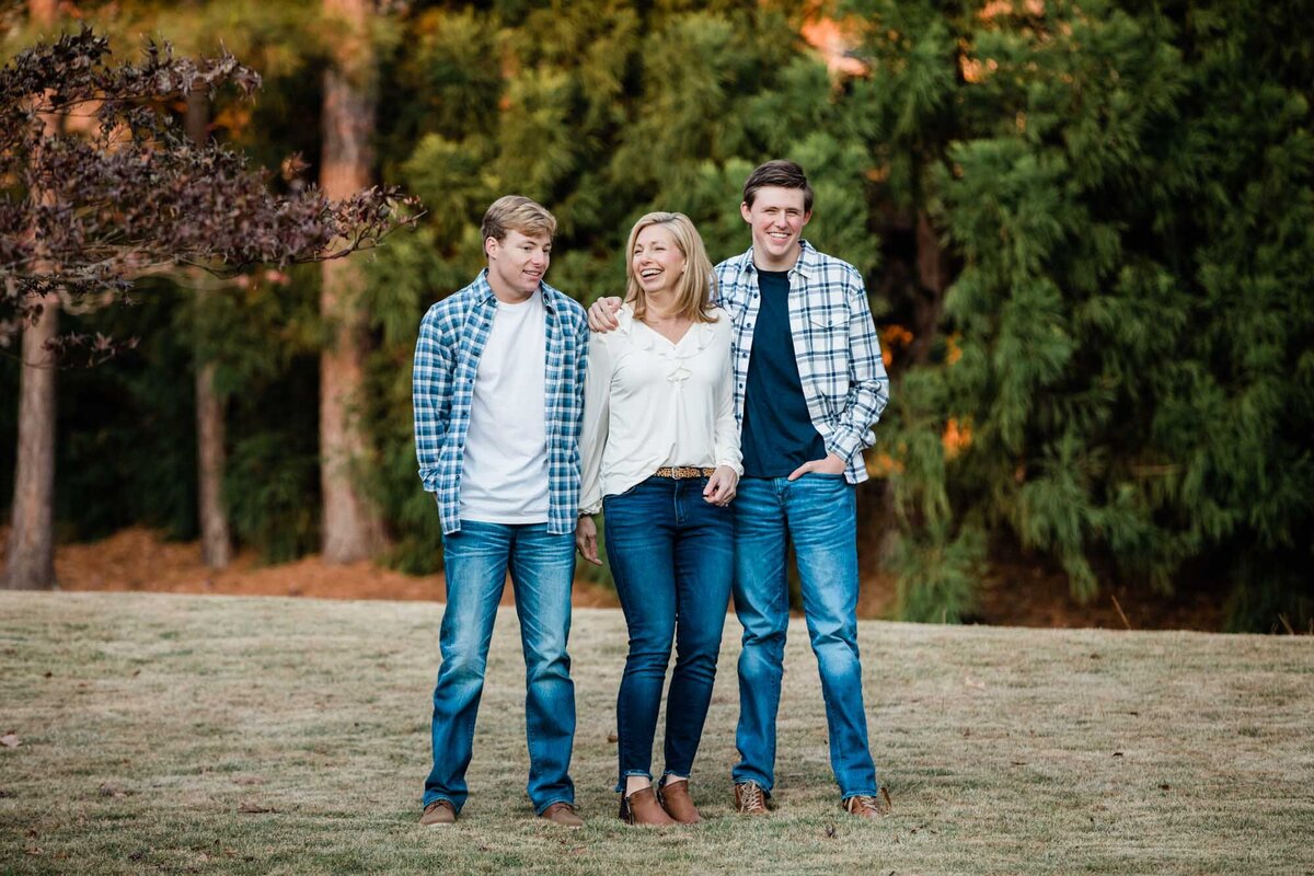 A mom and her two sons at a distance laughing at a joke someone told during their family portrait.