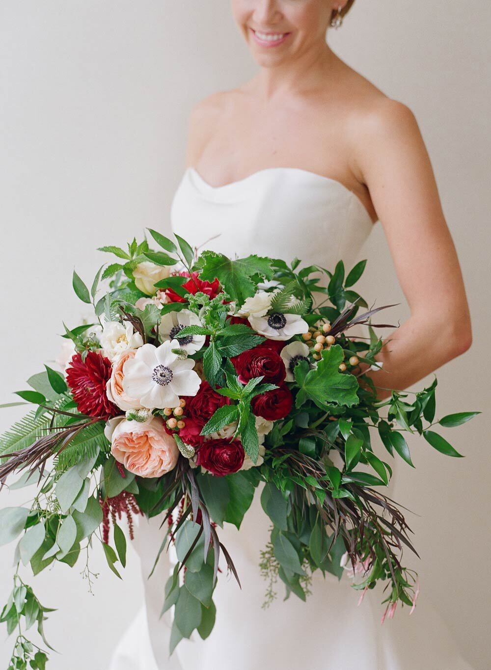 Bridal bouquet details with red, blush, and white flowers, and green leafy accents