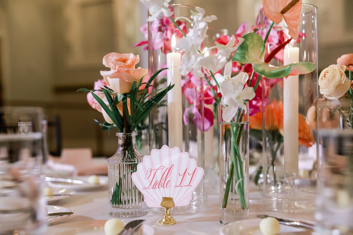 a table decorated with seashells and pink flower arrangements