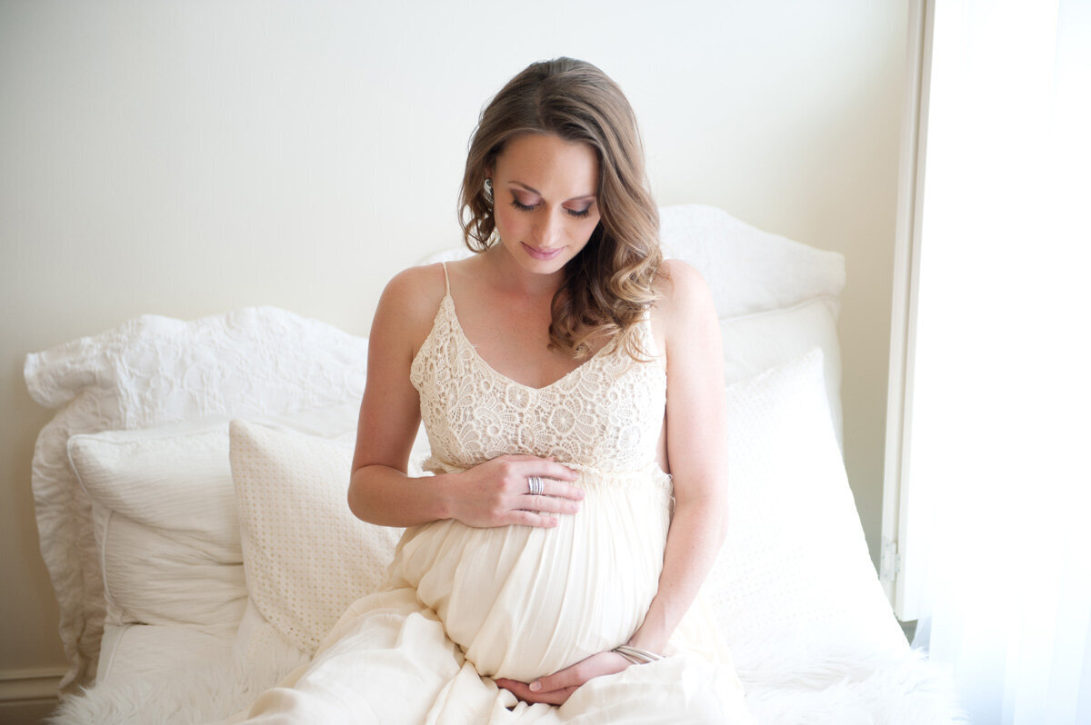 Maternity session located in home with woman sitting on bed