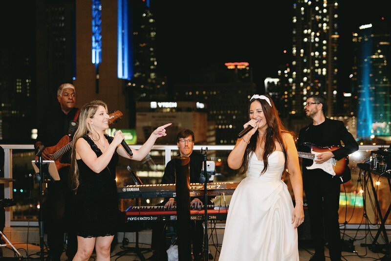 Bride singing with live band at penthouse at riverside wharf​