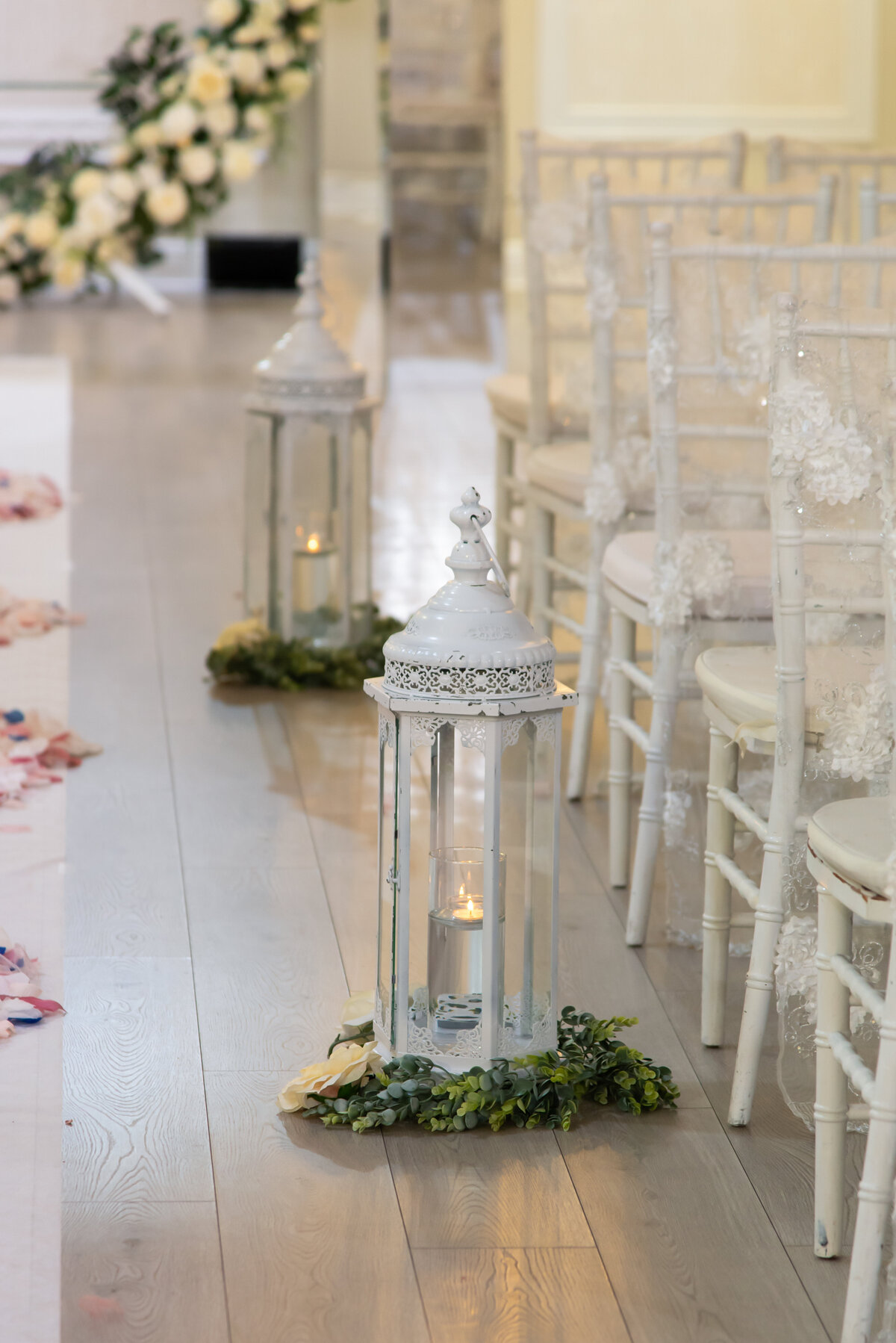 white candle lanterns lining ceremony aisle next to white chiavari chairs