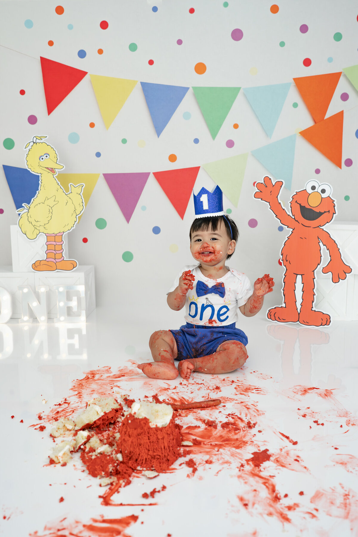 Boy in birthday outfit eating an Elmo cake during themed cake smash session— captured by Alliston and Barrie cake smash photographer.