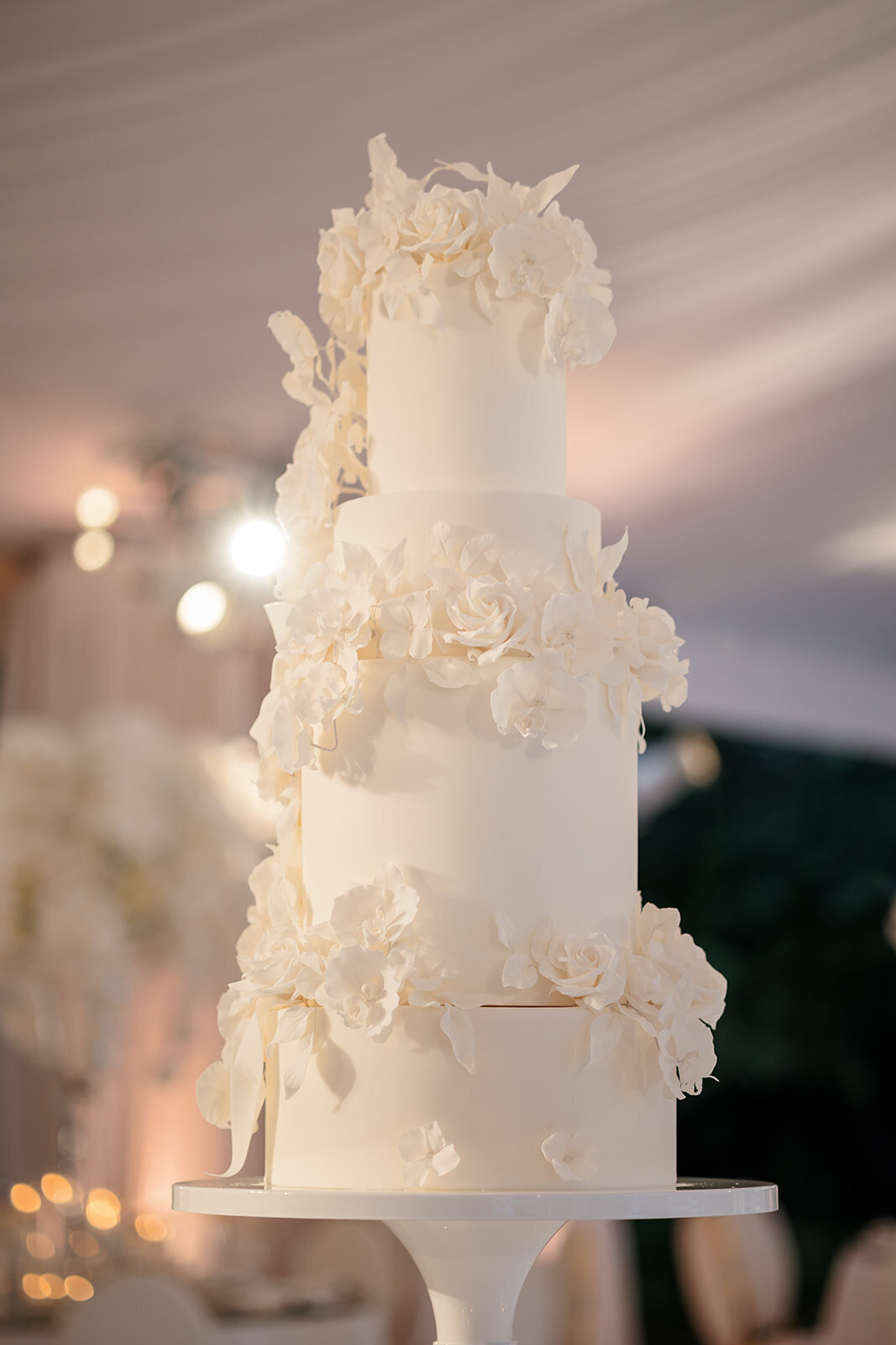 Towering white floral wedding cake adorned with delicate blossoms.