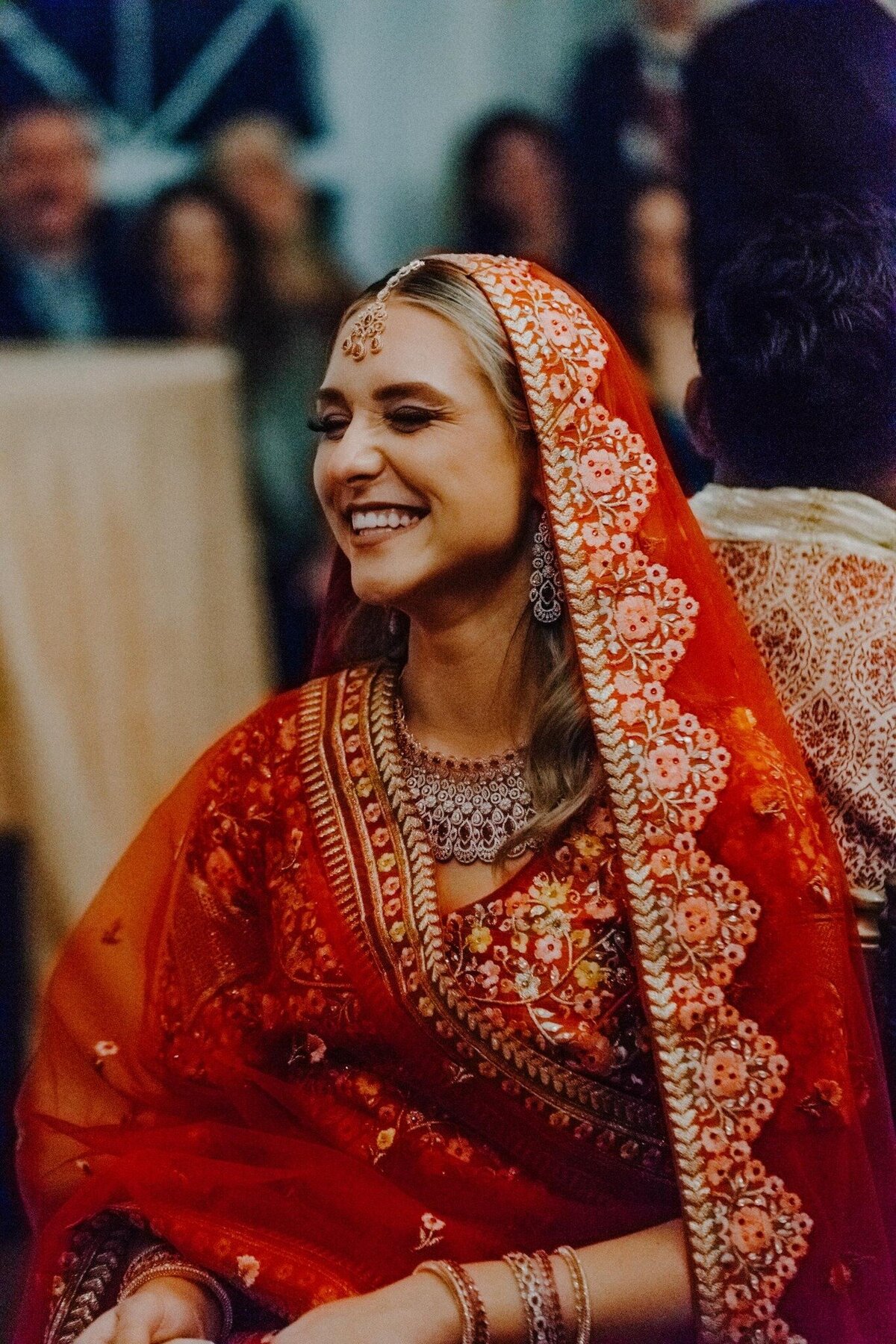 a bride at an indian wedding laughing at the ceremony