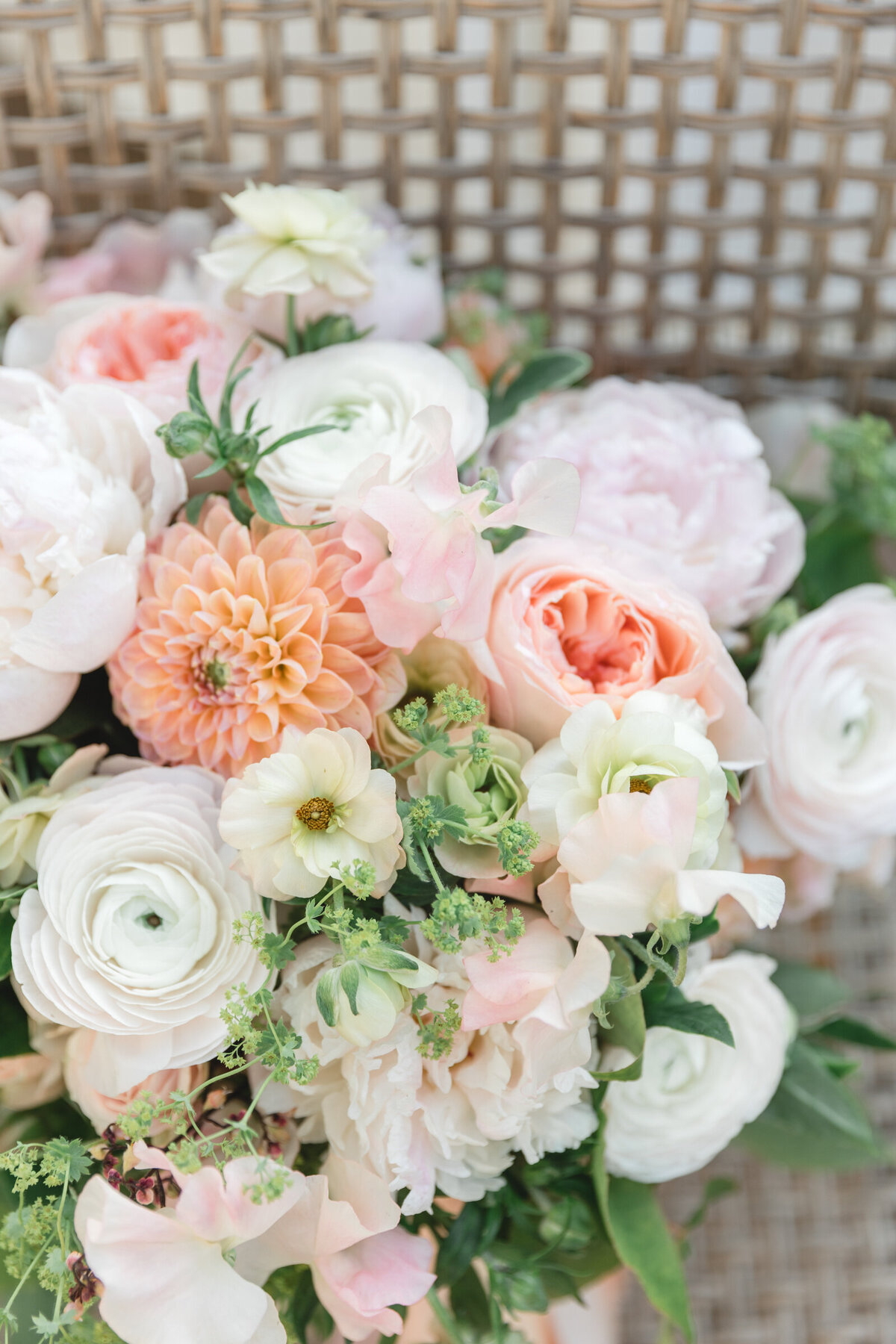 A close up of the bride's bouquet with dahlias, ranunculus,  butterfly ranunculus and greens