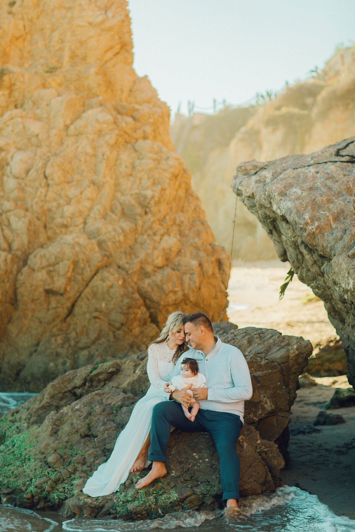 Family Portrait Photo Of Couple Holding Their Baby While Sitting On a Rock Formation Los Angeles