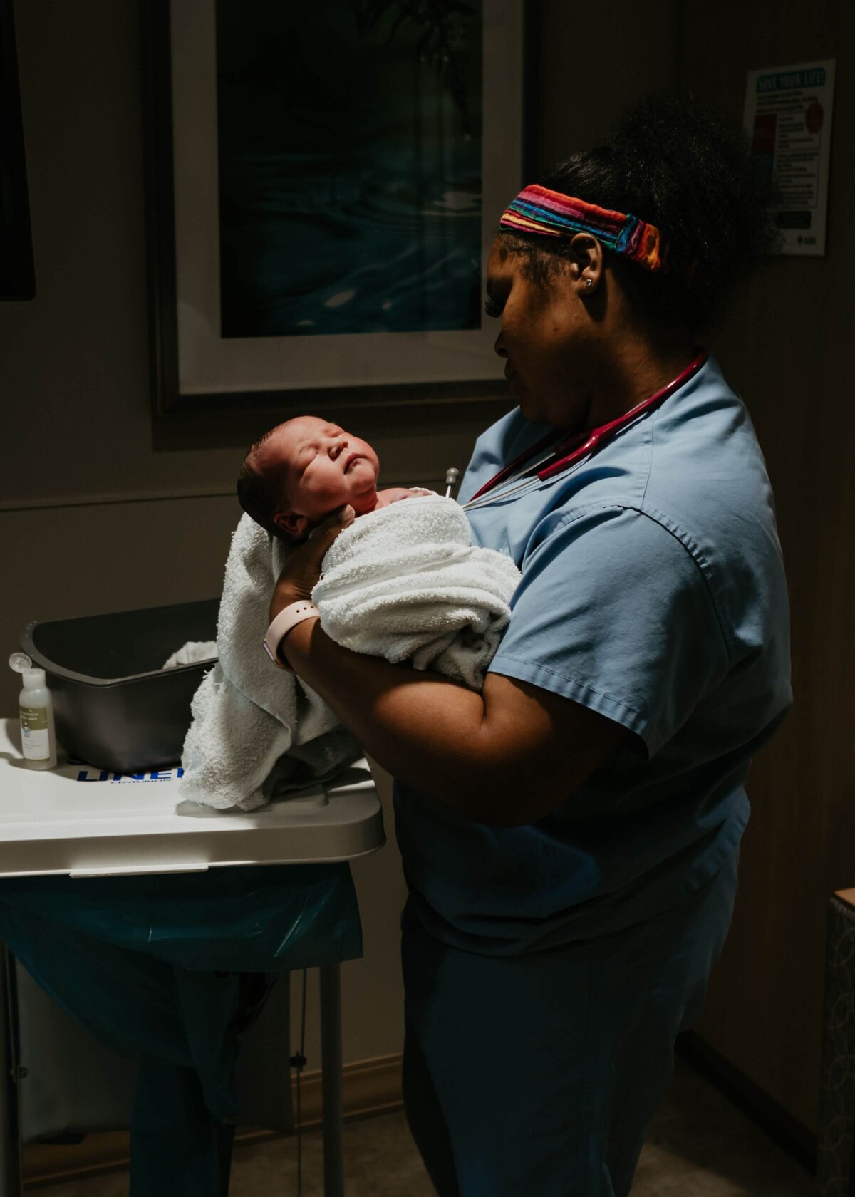 A nurse lovingly cradles a newborn in a hospital room.