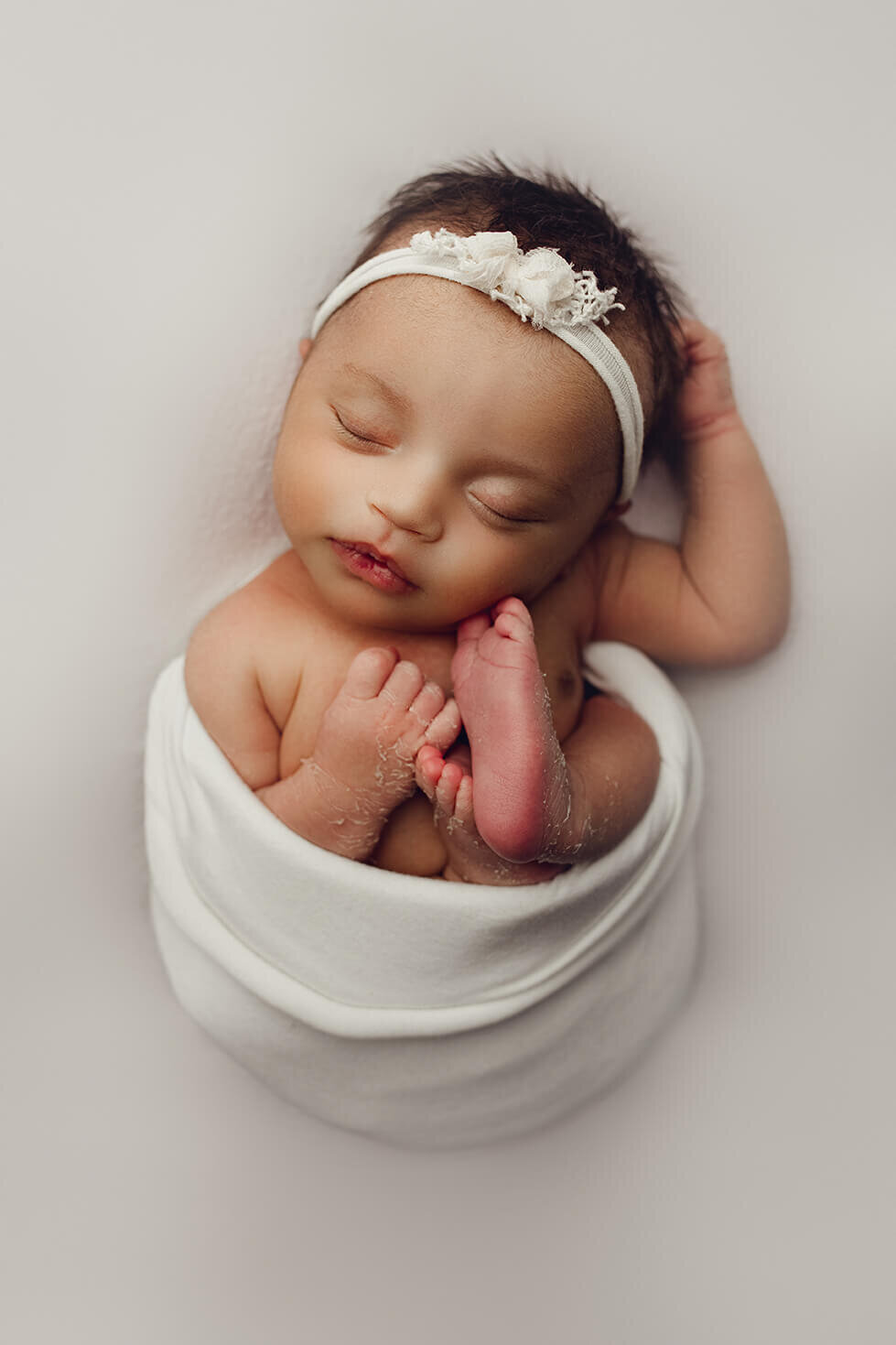 newborn girl wrapped up sleeping on her back