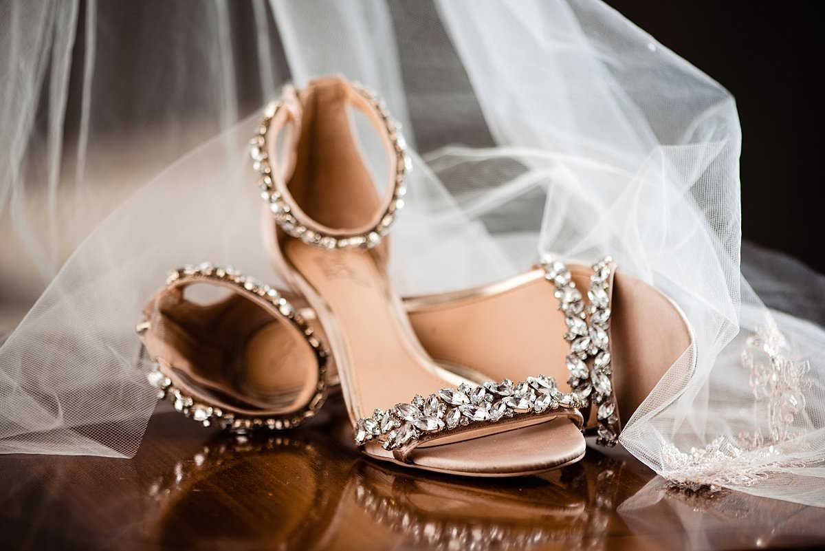 Brides wedding shoes with crystal detailing beside her wedding veil