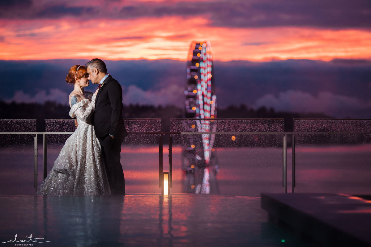 bride and groom embracing at sunset with Seattle ferris wheel in background