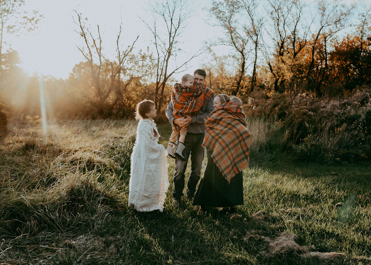 A beautiful, vibrant autumn, color, family portrait with three boys and their parents during a sunset session on their family farm.