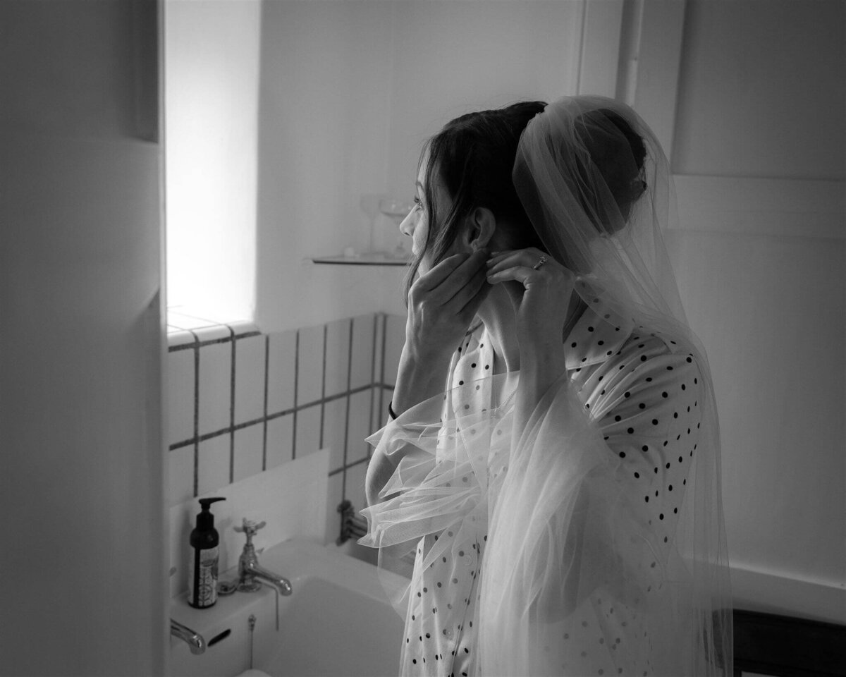 A bride in a Perth castle fixes and ear ring in the bathroom