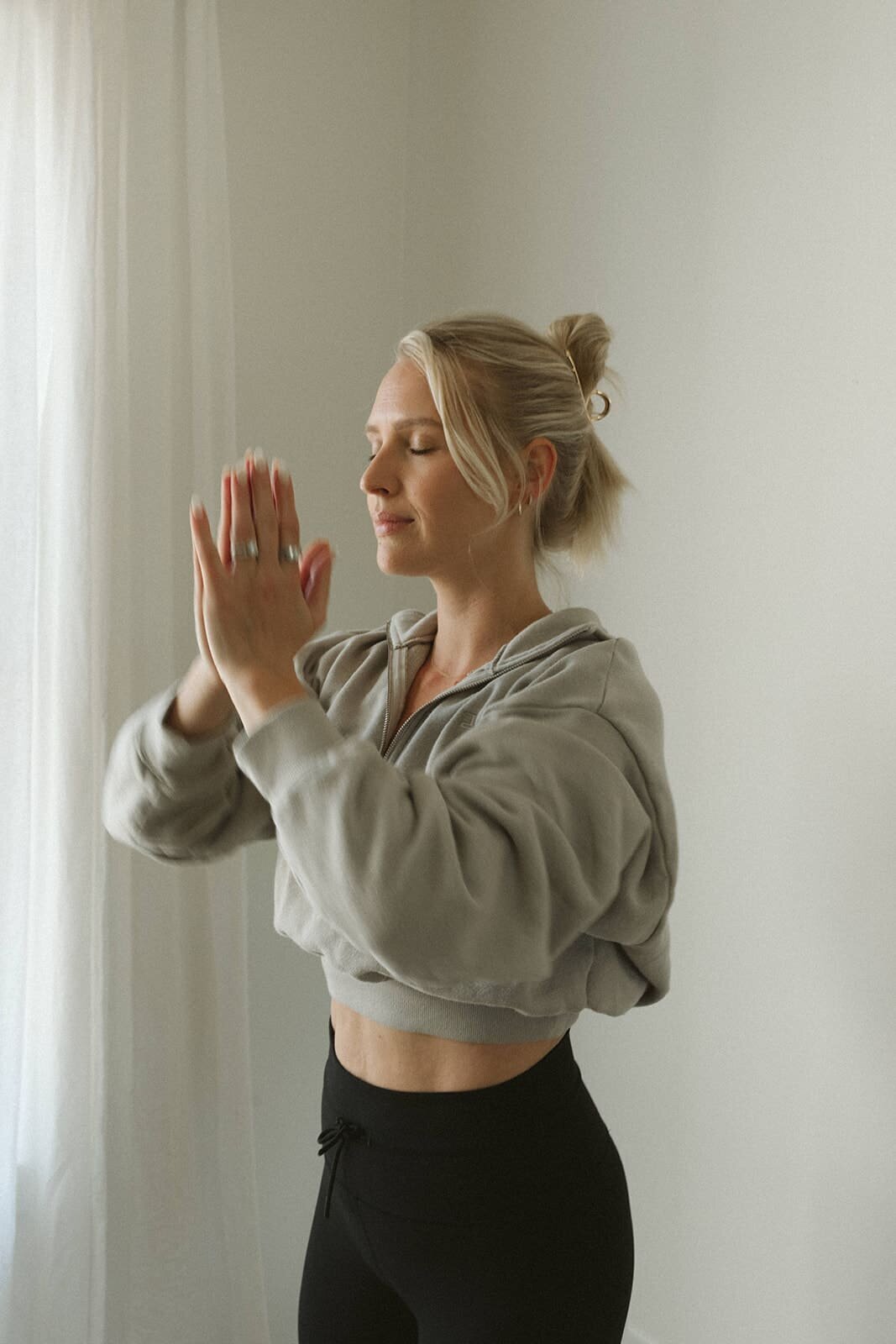 Woman standing in a prayer pose with eyes closed, embodying mindfulness and intentional movement