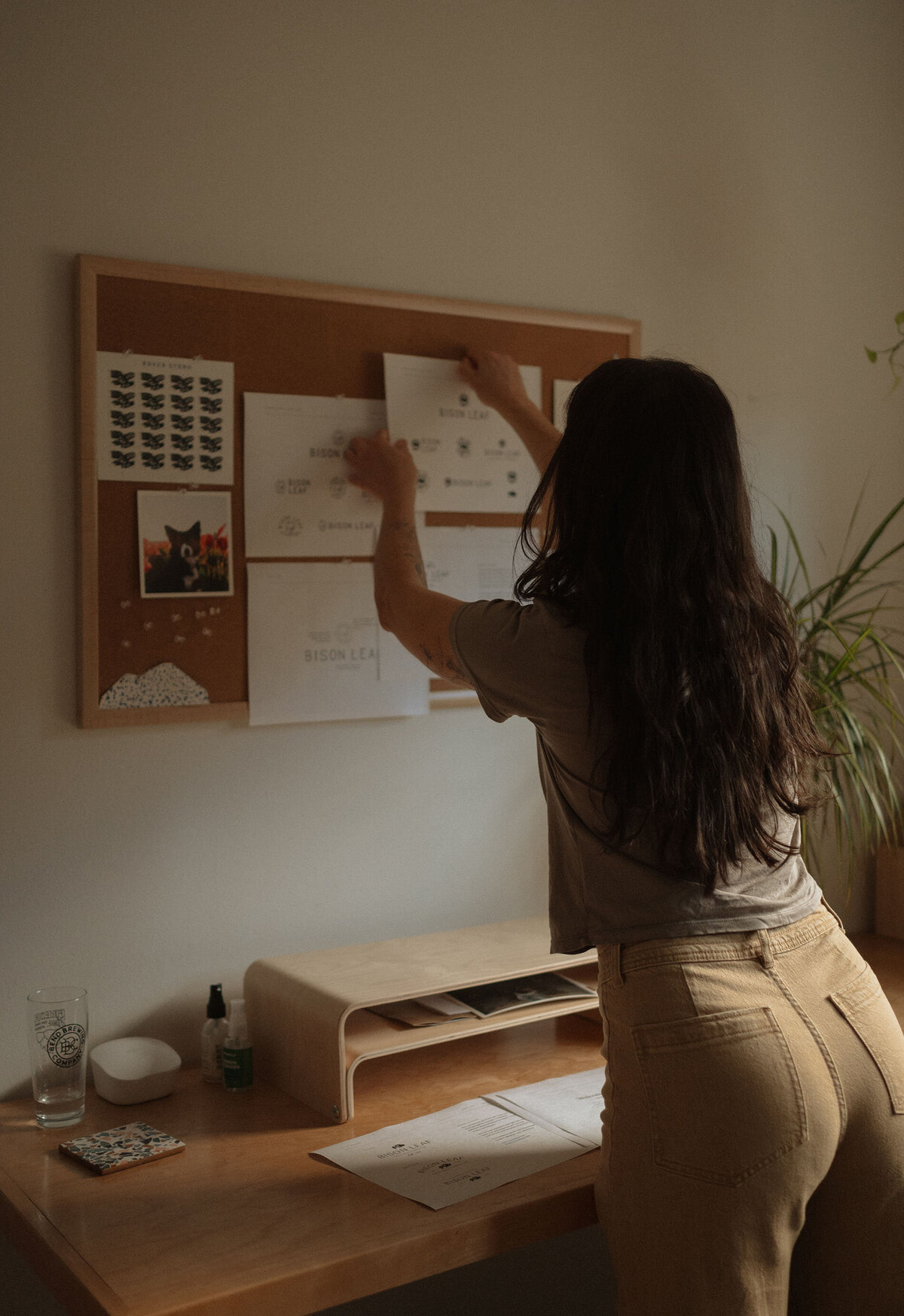 female business owner hangs up portfolio examples in her Bend, Oregon home during a branding photoshoot