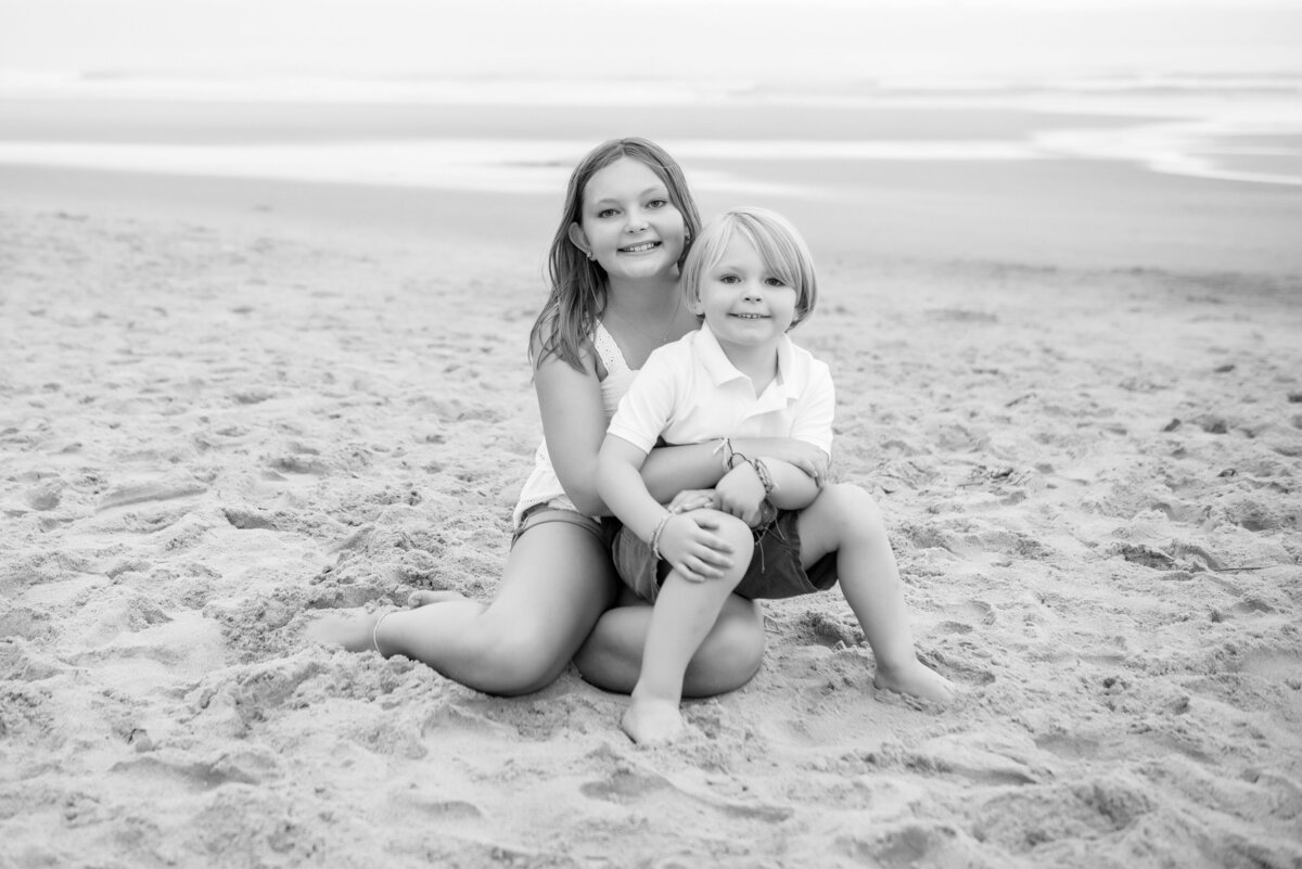 Black and white photo of two siblings on the beach