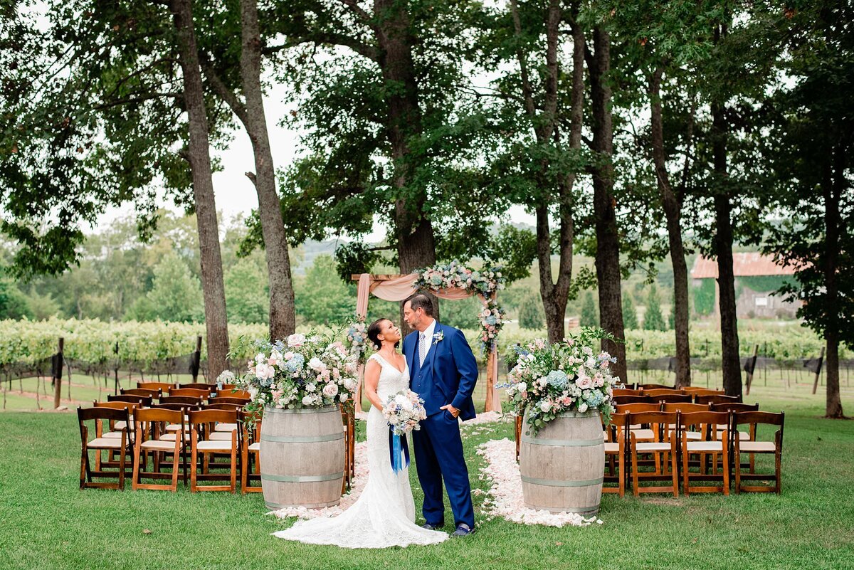 bride and groom kissing under a floral arbor at Arrington Vineyards