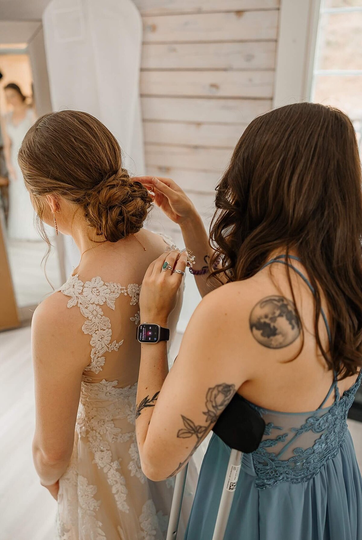 bride gets her hair fixed by her maid of honor in Colorado wedding venue