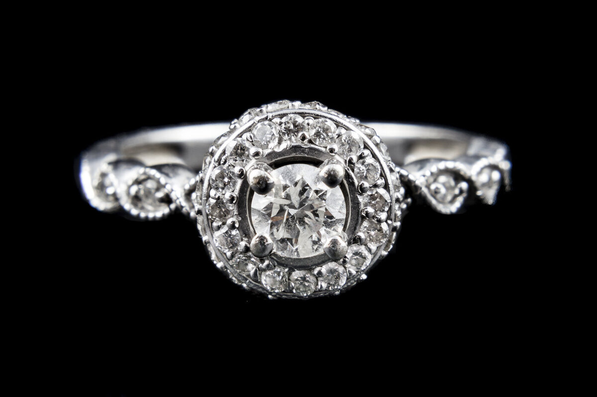 A close up photograph of an engagement ring with a black background.