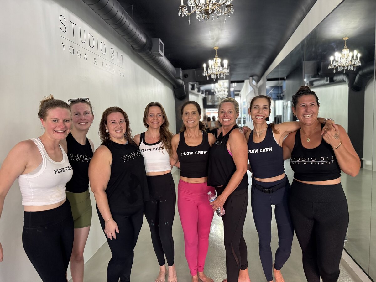 Several female yogis are modeling their Flow Crew and Studio 311 Ribbed Crop Tanks and Flowy Tanks.