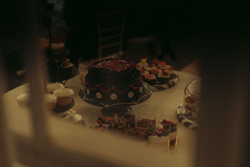 A wedding cake on a table with other desserts.