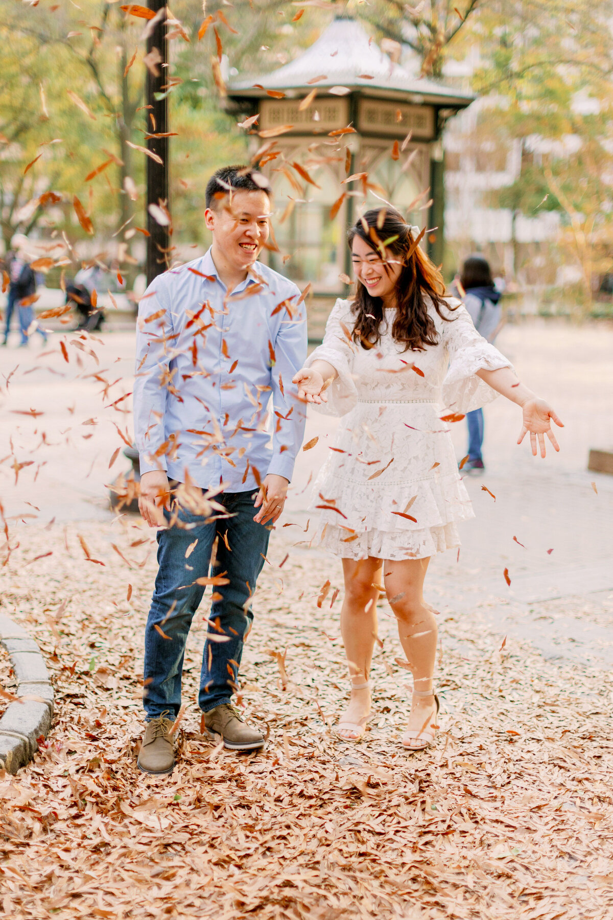 A couple laughing as they throw leaves around them 
