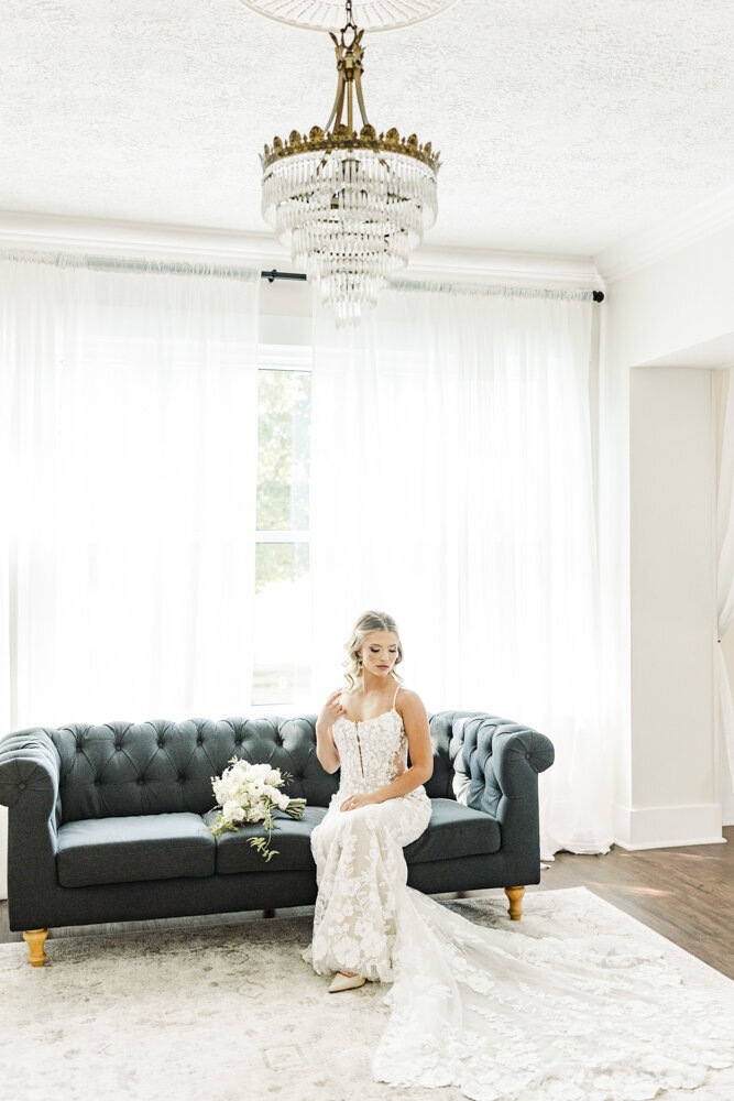 bride sitting on an emerald green couch in her wedding dress