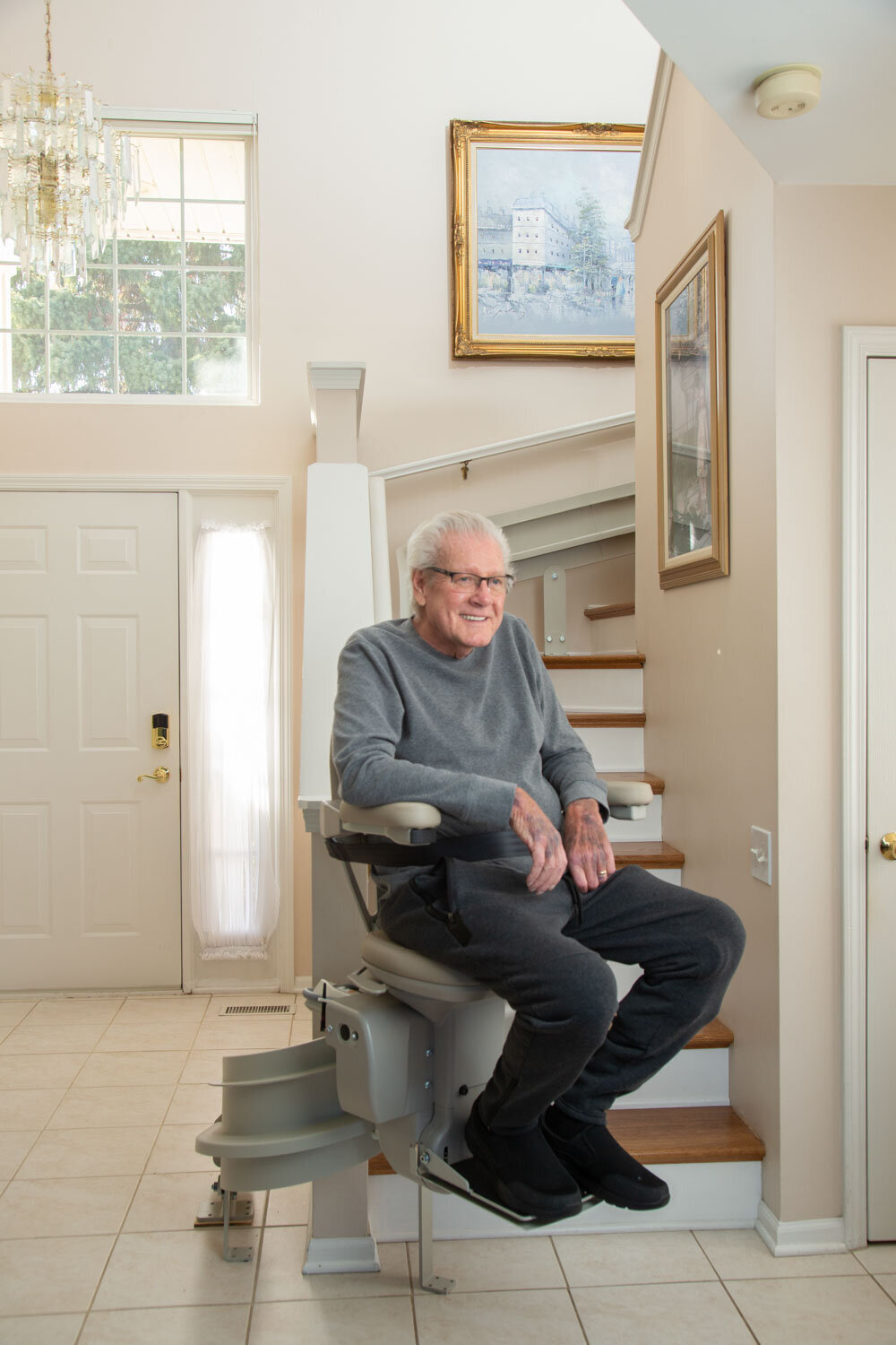 An older man is sitting on a mobility chair in front of stairs