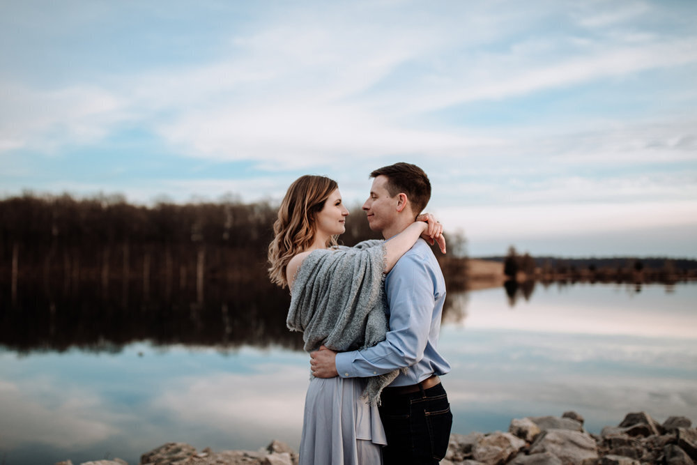 Bride and groom holding hands looking at each other while standing in front of rolling hills with the sunlight coming down on them