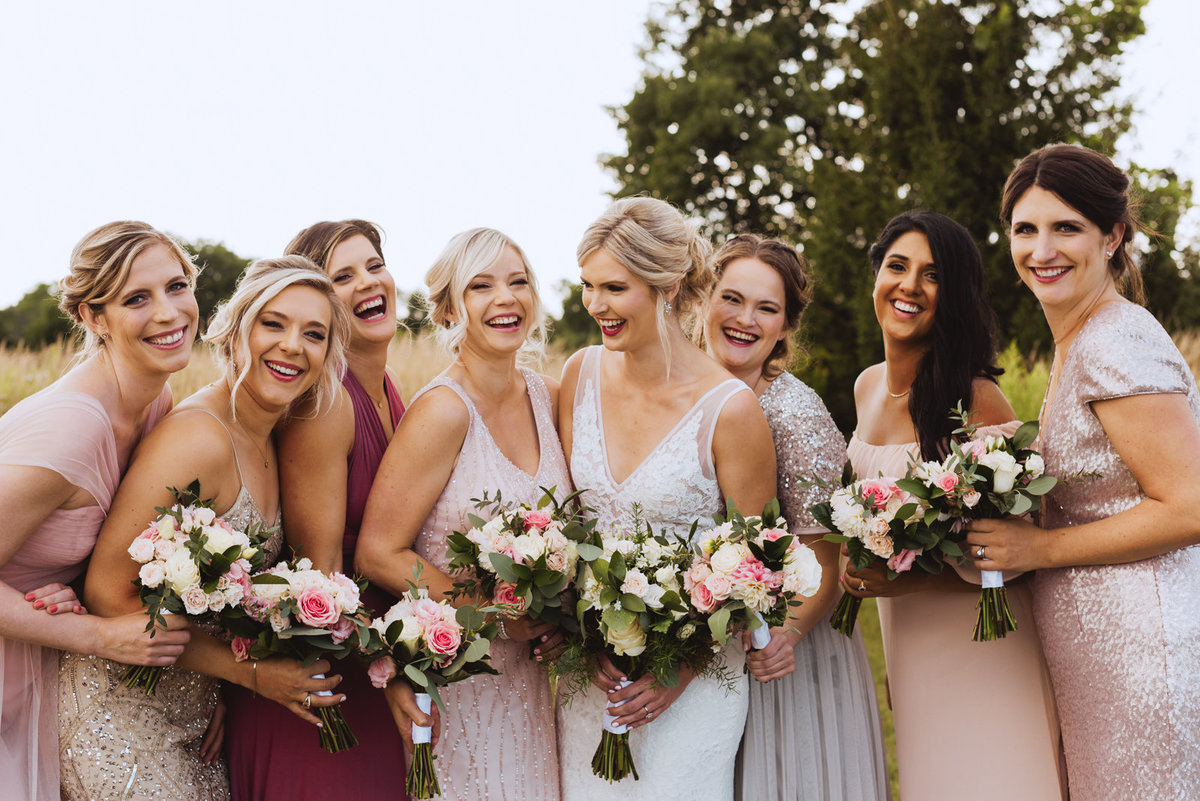 bride and bridesmaids laughing in a field