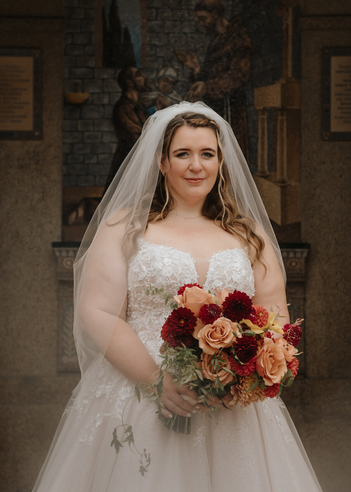 Bride stands outside of church in Washington DC holding a bouquet of flowers