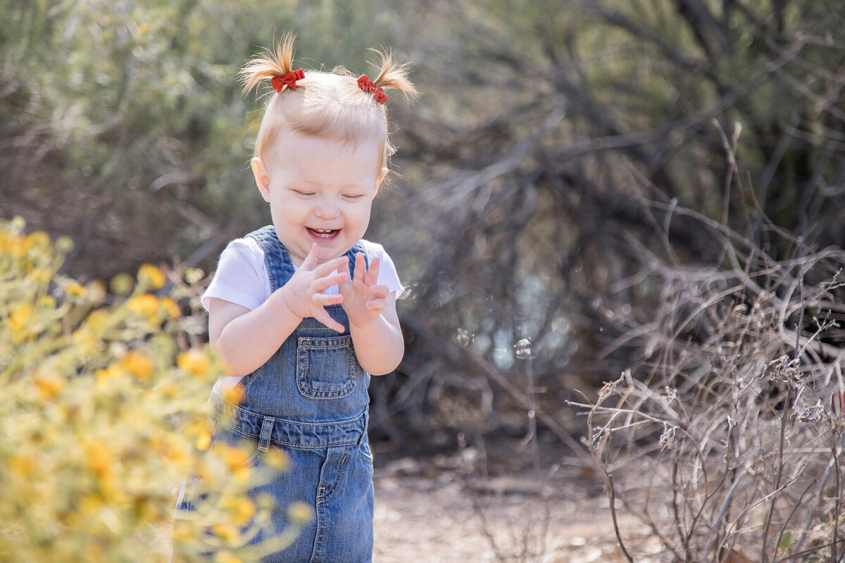 Happy toddler playing with her hands in desert park and laughing