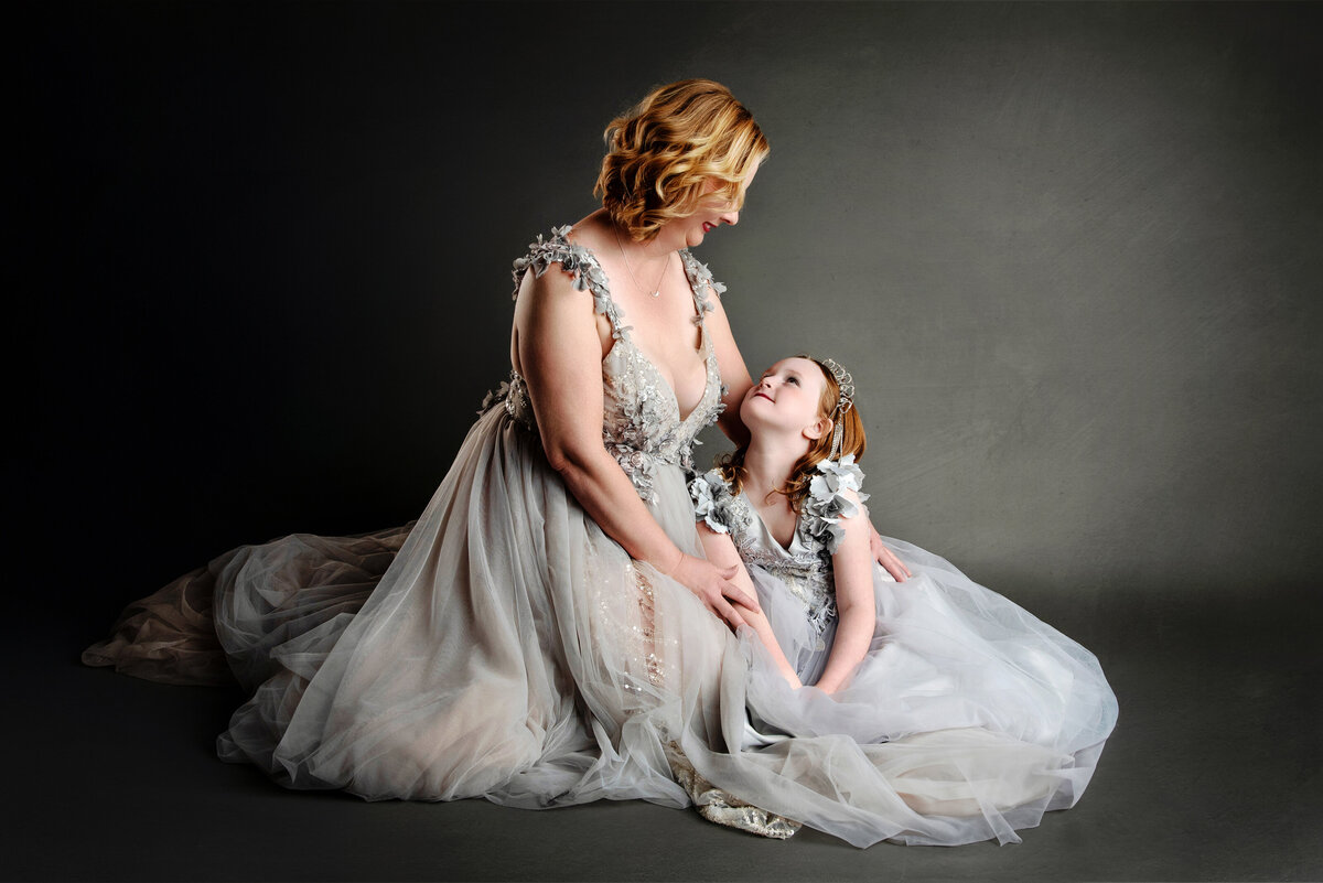 st-louis-family-photographer-mom-in-gray-tulle-gown-sitting-with-daughter-in-gray-dress-lookng-at-each-other