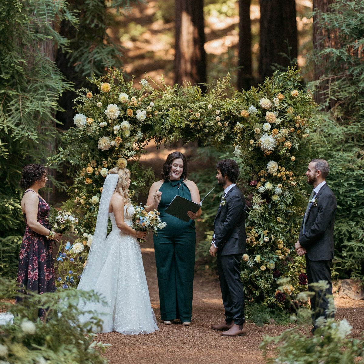 Intimate redwoods wedding ceremony in front of dramatic floral and foliage arch