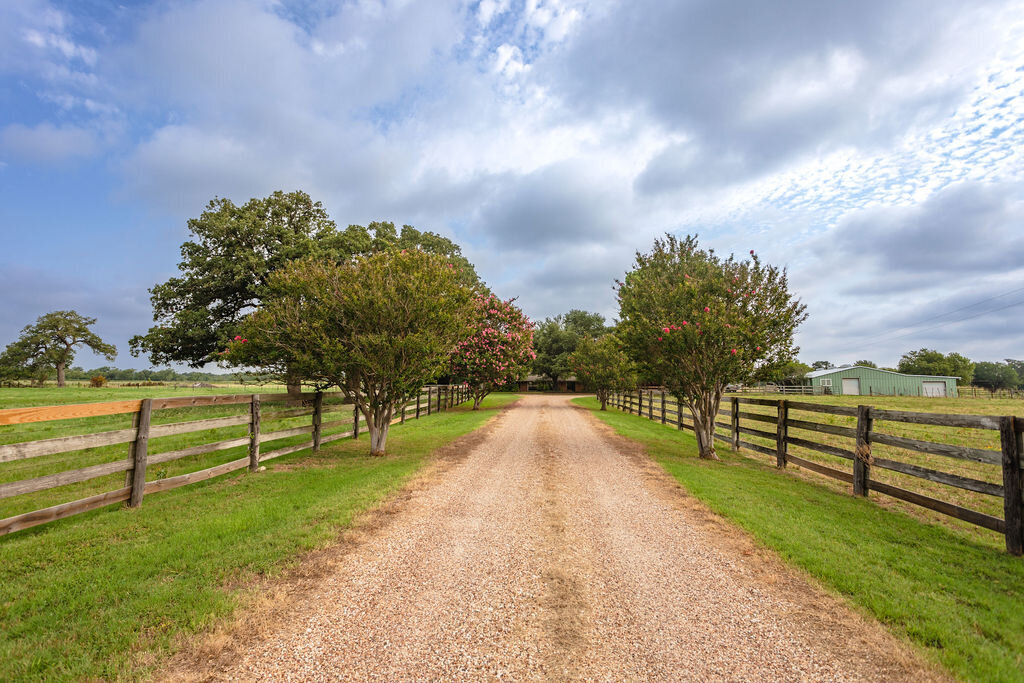 Large private driveway with beautiful oak trees at this 5-bedroom, 4-bathroom vacation rental house for 16+ guests with pool, free wifi, guesthouse and game room just 20 minutes away from downtown Waco, TX.