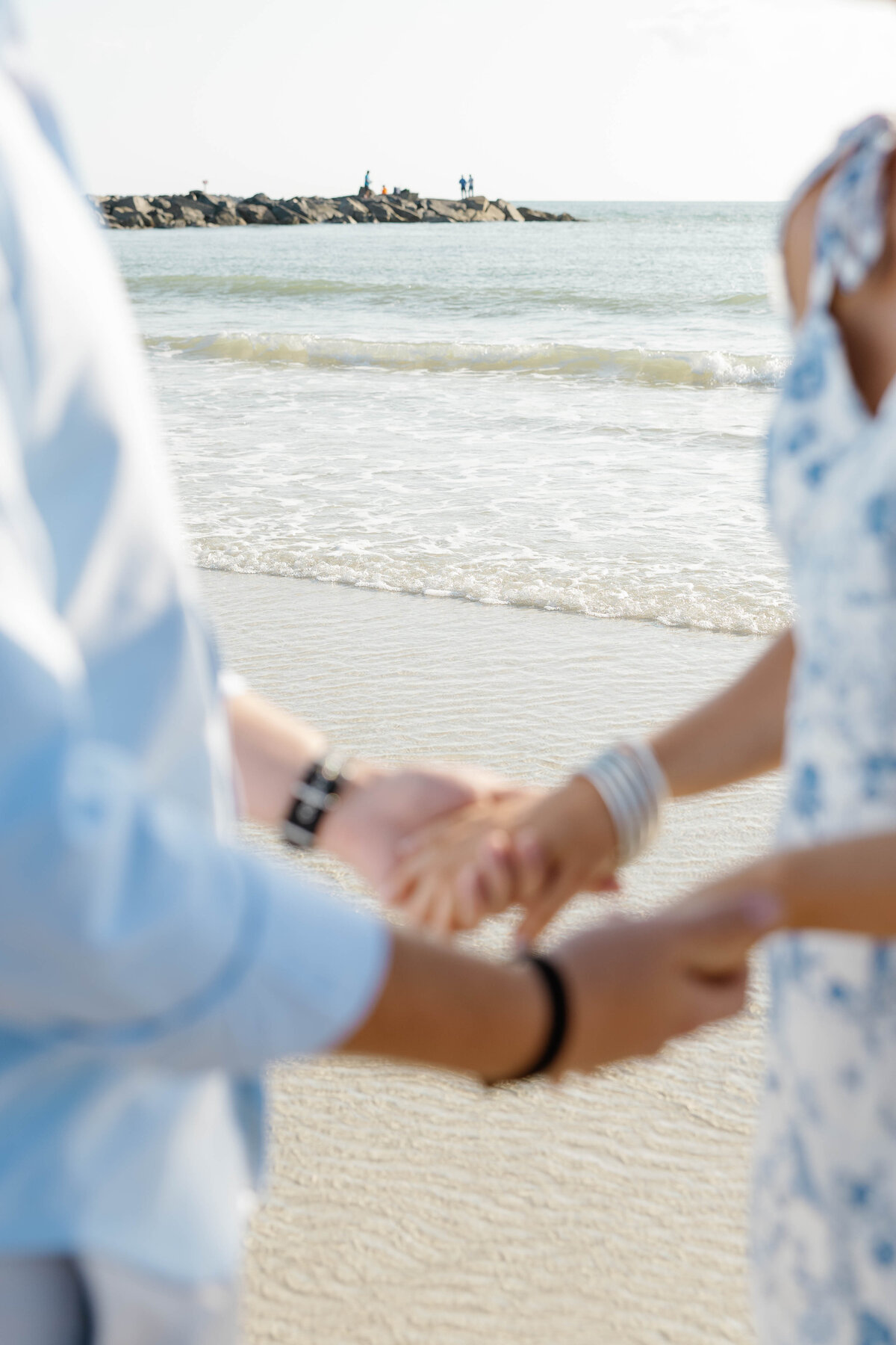 Engaged couple hold hands as the ocean rolls in at their feet at the Ponce Inlet