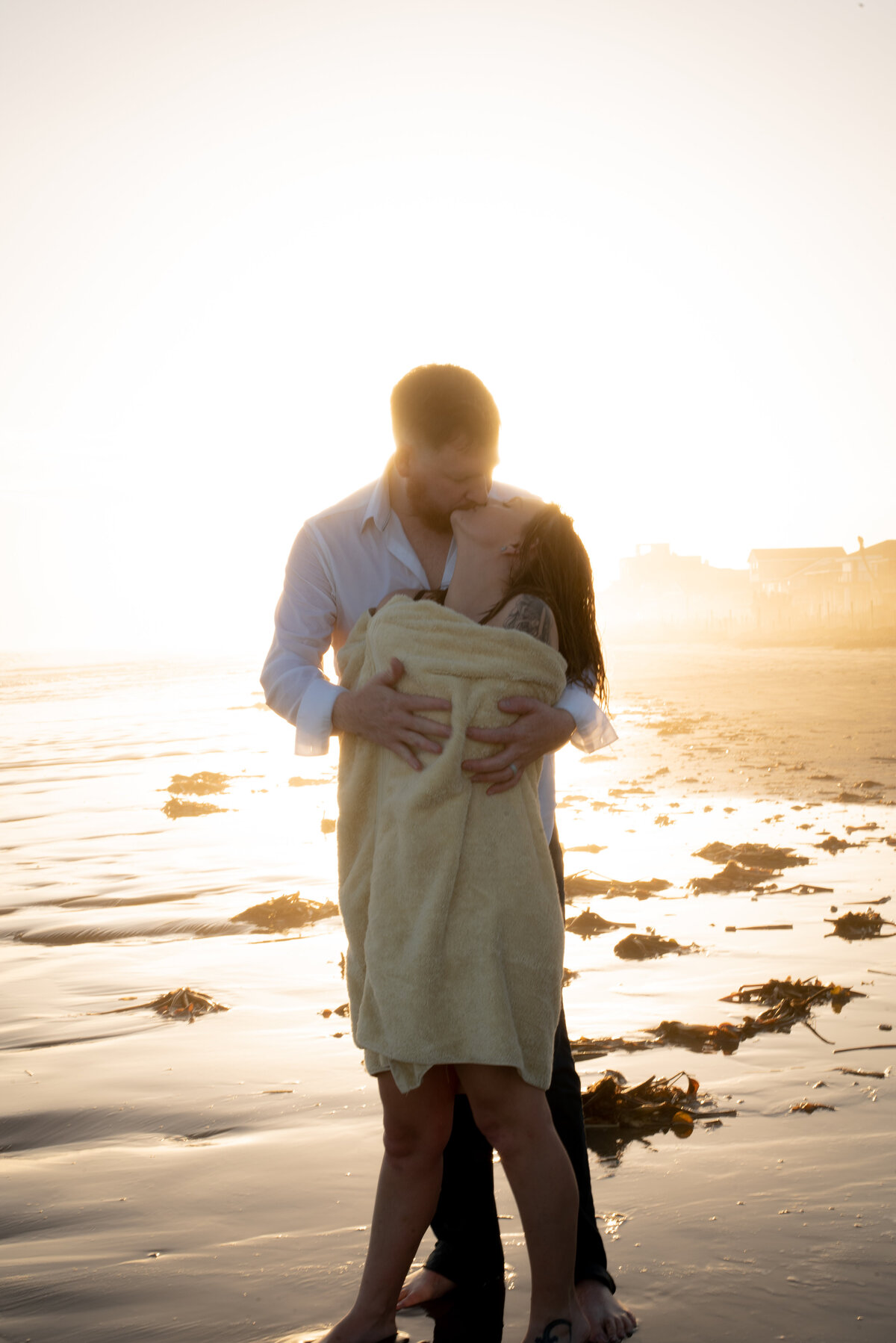 Embrace the warmth of a couple on the beach during a dreamy sunset, wrapped in a cozy blanket. Our photo captures the intimate connection as the sun sets on their day