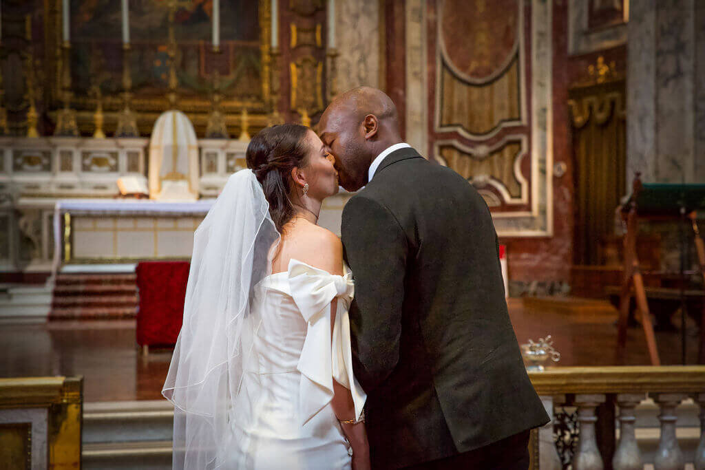 Bride kisses her groom .  Bride wearing white mini dress and mini veil.