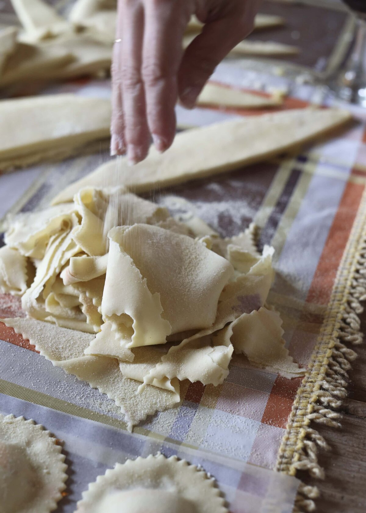 Pastie being made by hand on a white and orange table cloth.