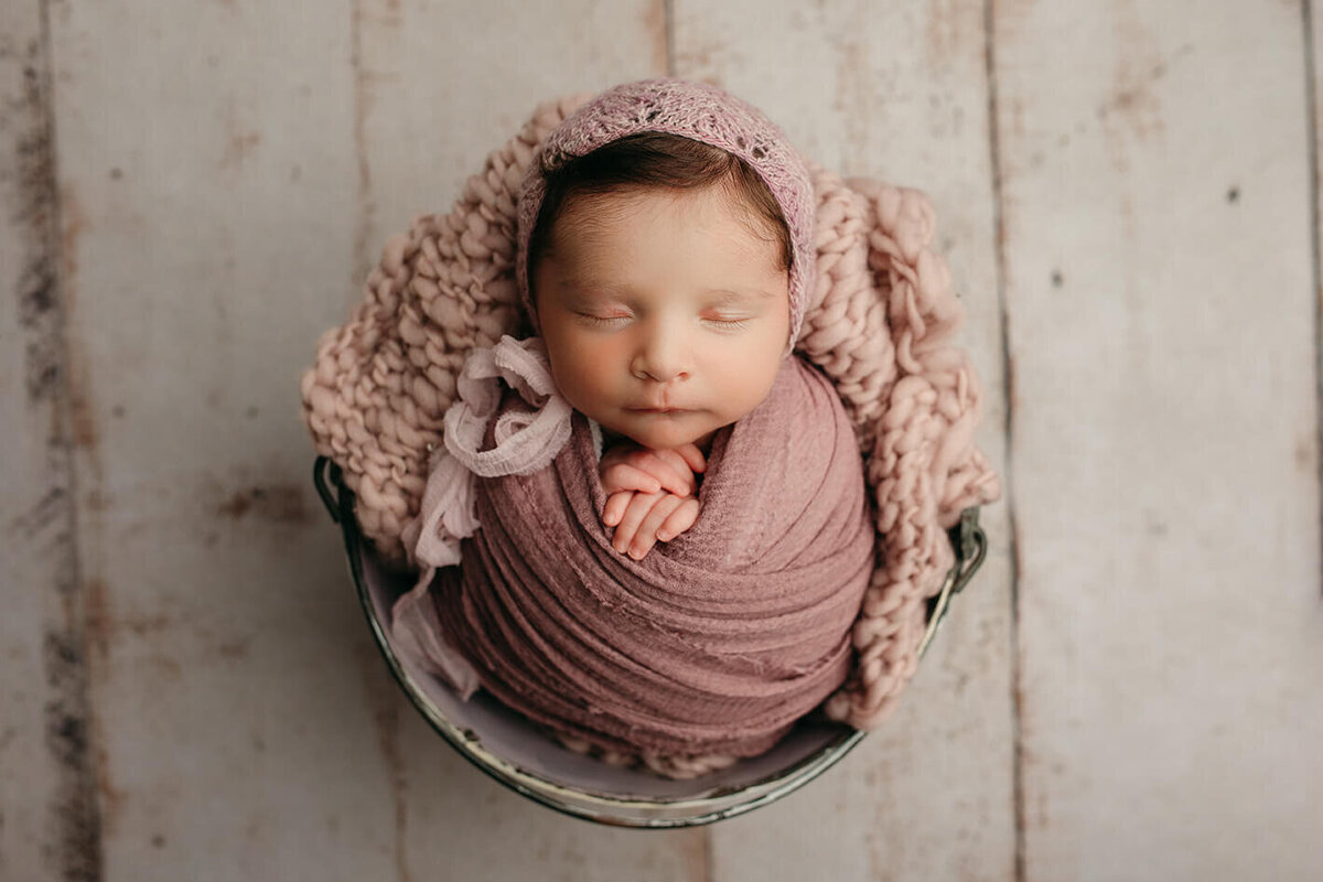 newborn baby girl in a purple wrap with a purple bonnet sleeping