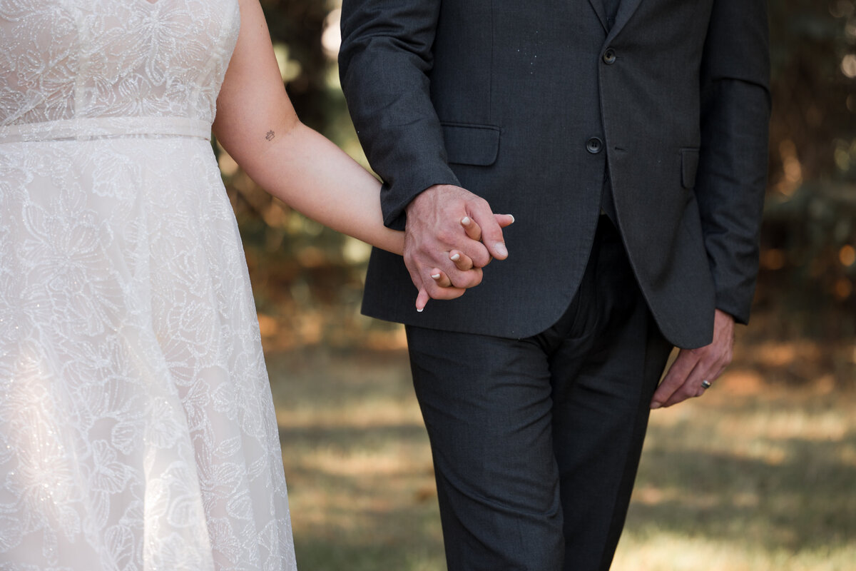 close up of bride and groom holding hands