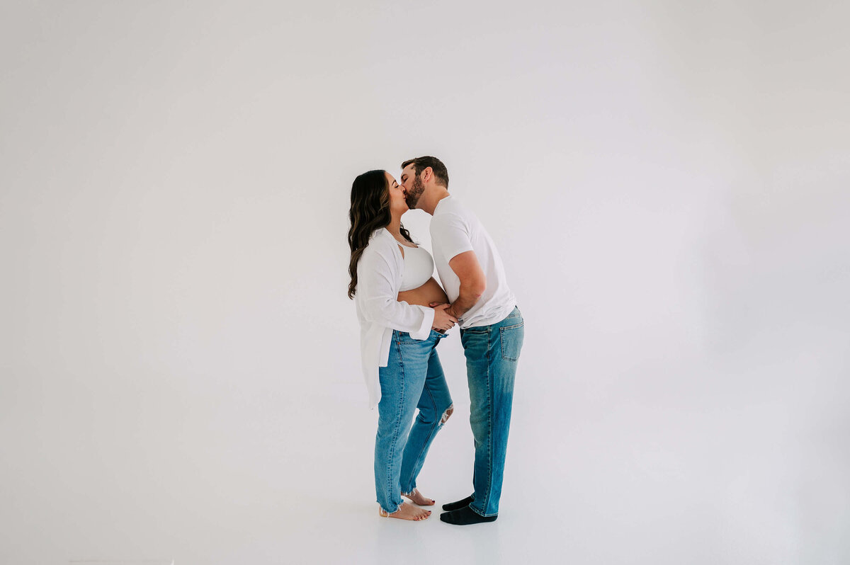 pregnant couple kissing in maternity photography studio in Joplin MO