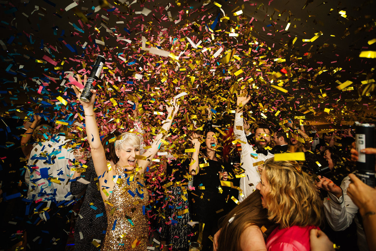 Bride wearing a gold evening party dress as Gold wedding confetti falls