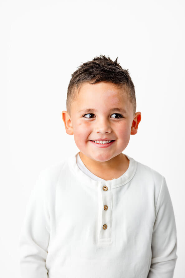 Boy smiles in white studio.