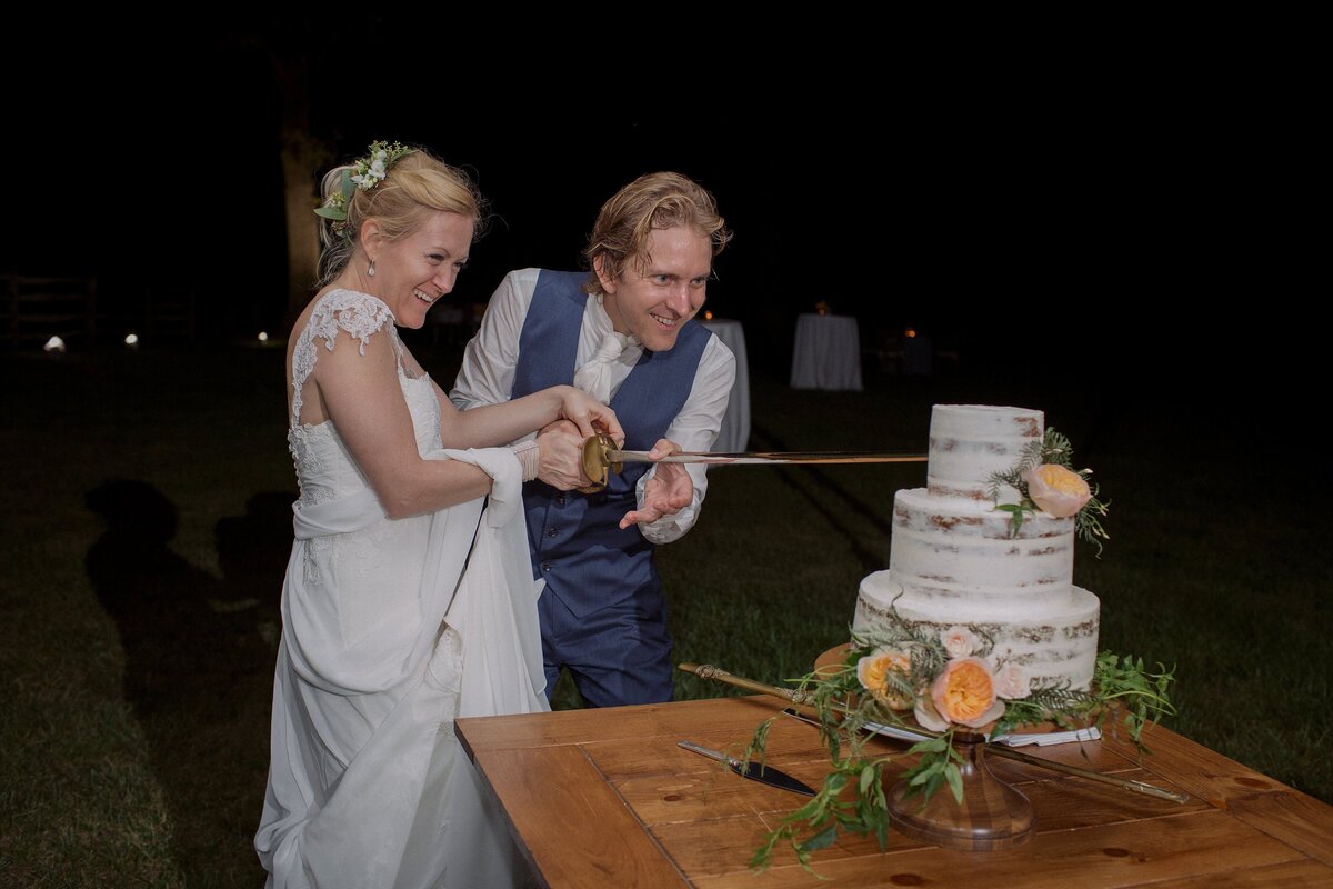 Couple cut wedding cake with heirloom swoard.