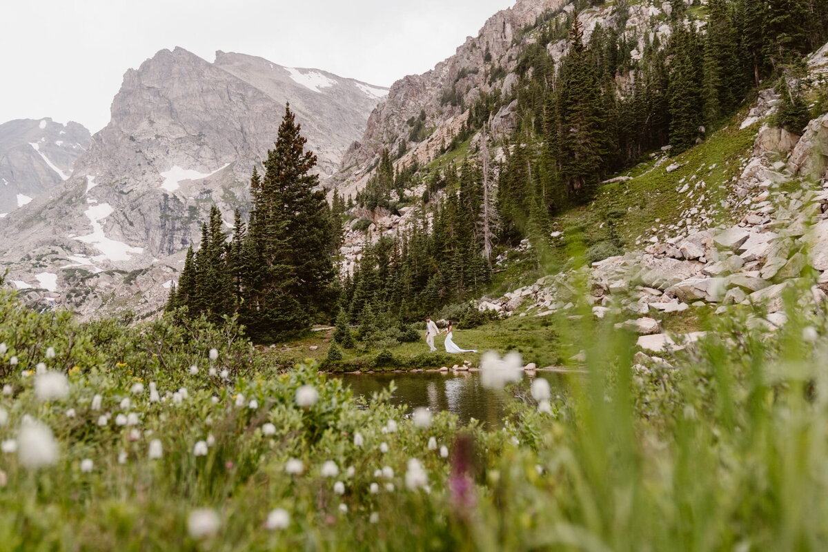 Colorado adventure elopement photographer captures a couple exploring Lake Isabelle in the Indian Peaks Wilderness surrounded by wildflowers and mountain peaks.
