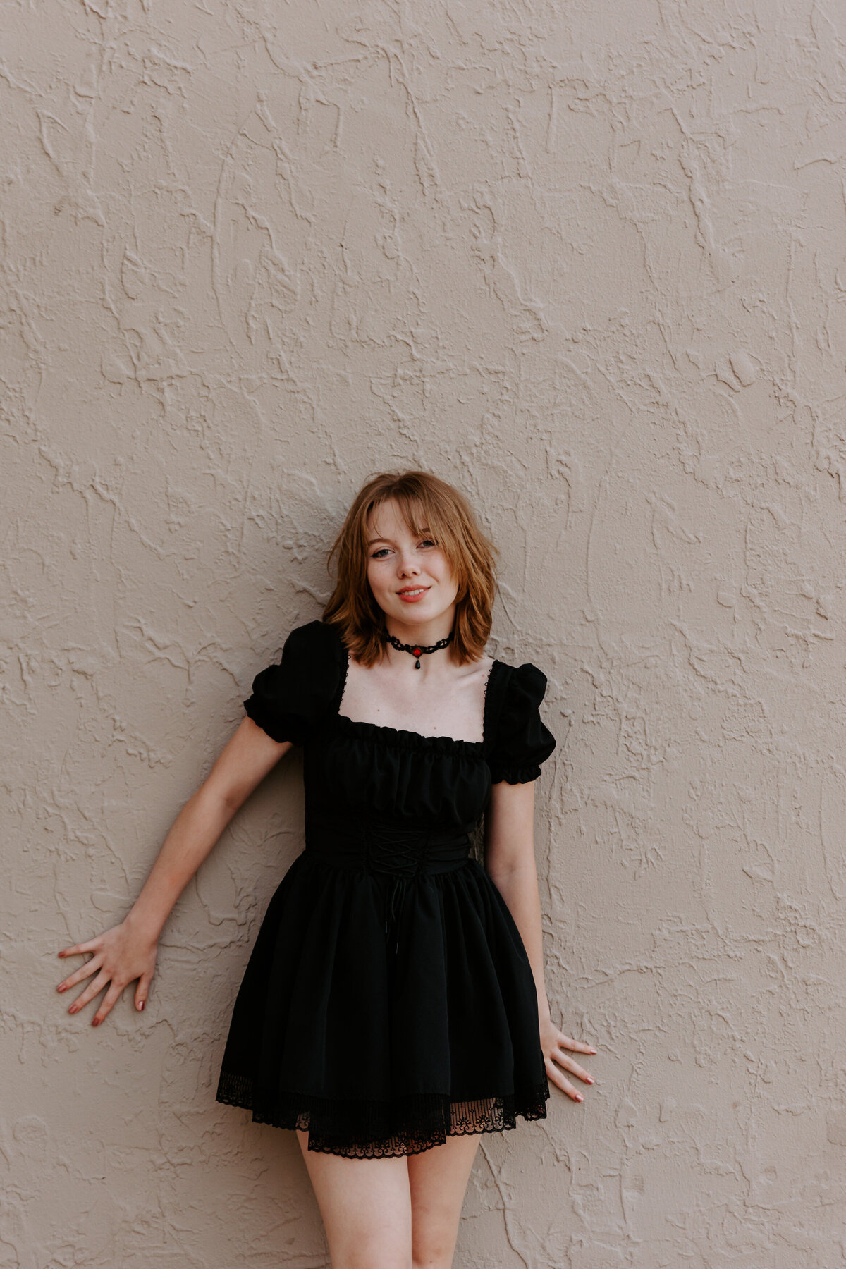 A girl leaning up against a wall smiling